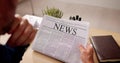 Businessman Reading Newspaper At Office Desk