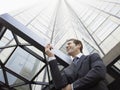 Businessman Reading SMS On Mobile Phone Against Office Building Royalty Free Stock Photo