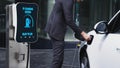 Businessman recharge his electric car from charging station. Peruse