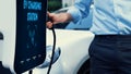 Businessman recharge his electric car from charging station. Peruse