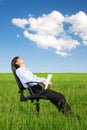 Businessman relaxing on grassland under blue sky Royalty Free Stock Photo