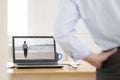 Businessman relaxing at his workplace at home while watching on a laptop a businessman walking on a beach