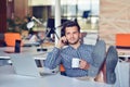 Businessman relaxing with legs up on desk, drinking coffee while dreaming about future at workplace in modern office. Royalty Free Stock Photo