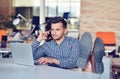 Businessman relaxing with legs up on desk, drinking coffee while dreaming about future at workplace in modern office. Royalty Free Stock Photo