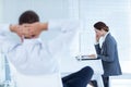 Businessman relaxing in a swivel chair while his colleague reading file Royalty Free Stock Photo