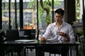 A businessman remote working at a coffee shop, sipping coffee and taking notes on his notebook Royalty Free Stock Photo