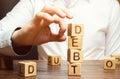 Businessman removes wooden blocks with the word Debt. Reduction or restructuring of debt. Bankruptcy announcement. Refusal to pay Royalty Free Stock Photo