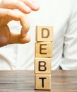 Businessman removes wooden blocks with the word Debt. Reduction or restructuring of debt. Bankruptcy announcement. Refusal to pay Royalty Free Stock Photo