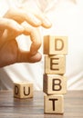 Businessman removes wooden blocks with the word Debt. Reduction or restructuring of debt. Bankruptcy announcement. Refusal to pay Royalty Free Stock Photo