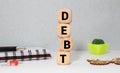 Businessman removes wooden blocks with the word Debt. Reduction or restructuring of debt. Bankruptcy announcement Royalty Free Stock Photo