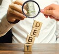 Businessman removes wooden blocks with the word Debt. Debt relief or cancellation is the partial or total forgiveness of debts, or