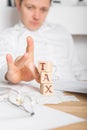 Businessman removes wooden blocks with the word Tax. Reduction or restructuring of debt. Bankruptcy announcement. Refusal to pay Royalty Free Stock Photo