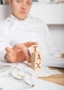 Businessman removes wooden blocks with the word Tax. Reduction or restructuring of debt. Bankruptcy announcement. Refusal to pay Royalty Free Stock Photo