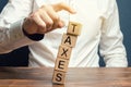 Businessman removes wooden blocks with the word Taxes. The concept of tax payment for housing and property. Income / goods tax.