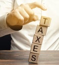 Businessman removes wooden blocks with the word Taxes. The concept of tax payment for housing and property. Income / goods tax.