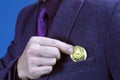 Businessman removing or placing a golden bitcoin in a pocket of his suit jacket in a wide close up view Royalty Free Stock Photo
