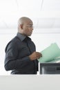 Businessman Reviewing File At Computer Desk