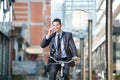 Businessman riding a bicycle and talking with mobile phone Royalty Free Stock Photo