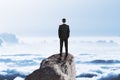 Businessman on rock above clouds