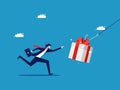 Businessman runs to grab a gift box as bait