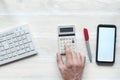 Businessman`s hand on a calculator. Telephone and computer keyboard. On a wooden background Royalty Free Stock Photo