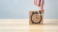 businessman`s hand holding and assemble wooden cube with icon alarm clock shape. Royalty Free Stock Photo