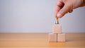 Businessman's hand holding a king placed on the topmost layer of wood. represents the concept of competition and strategic