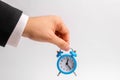 A businessman`s hand holds a blue alarm clock on a white background. The concept of the flow of time, time to action. Hourly pay