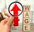 Businessman`s hand holds red arrow up near wooden blocks with word Wage. Salary increase concept. Wages rate. Revenue growth and