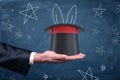 A businessman`s palm with a magician`s hat resting on it and drawings of stars and rabbit ears around. Royalty Free Stock Photo