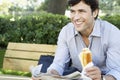 Businessman With Sandwich And Newspaper Sitting On Bench At Park Royalty Free Stock Photo