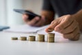 Businessman saving money concept financial. hand holding coins putting on stack using smartphone Royalty Free Stock Photo