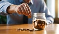 businessman saving money concept. hand holding coins putting in jug glass Royalty Free Stock Photo