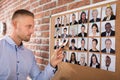 Businessman Selecting Candidates Photo On Corkboard