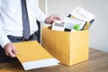 Businessman sending letter will being resignation and carrying packing belongings company and files into brown cardboard box, Royalty Free Stock Photo