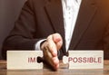 Businessman separates puzzles with the word Impossible. The concept of self-motivation and achievement of goals. Business Royalty Free Stock Photo