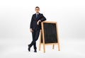 Businessman with a serious face leaning on the small blackboard