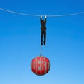 Businessman shackled by debt ball hanging on rope blue background