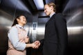 Businessman shaking hands with businesswoman in elevator Royalty Free Stock Photo