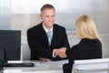 Businessman Shaking Hands With Female Candidate At Desk Royalty Free Stock Photo