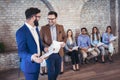 Businessman shaking hands with man besides people waiting for job interview Royalty Free Stock Photo