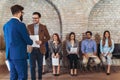 Businessman shaking hands with man besides people waiting for job interview Royalty Free Stock Photo