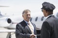 Businessman Shaking Hands With Pilot And Aircraft In Background Royalty Free Stock Photo