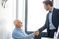 businessman shaking hands with seated male senior citizen