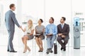 Businessman shaking hands with woman besides people waiting for interview Royalty Free Stock Photo