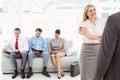 Businessman shaking hands with woman besides people waiting for interview Royalty Free Stock Photo