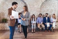 Businessman shaking hands with woman besides people waiting for job interview Royalty Free Stock Photo