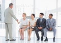 Businessman shaking hands with woman by people waiting for interview