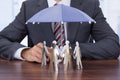 Businessman sheltering paper people with umbrella Royalty Free Stock Photo