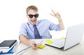 Businessman in shirt and tie sitting at office computer desk holding selfie stick shooting self portrait photo